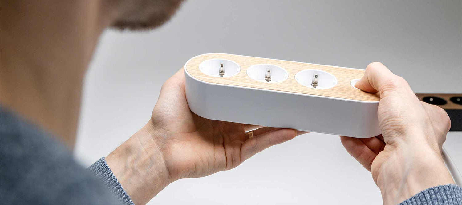 Miska Karvinen holding and inspecting white design power strip MyNolla White/oak